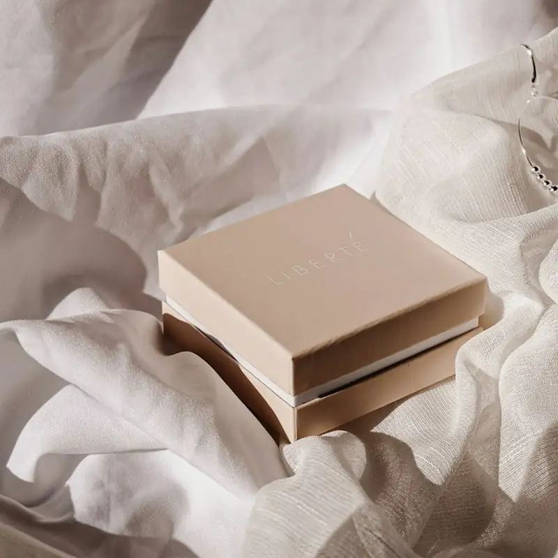 A kraft rigid box with a lid resting on white satin