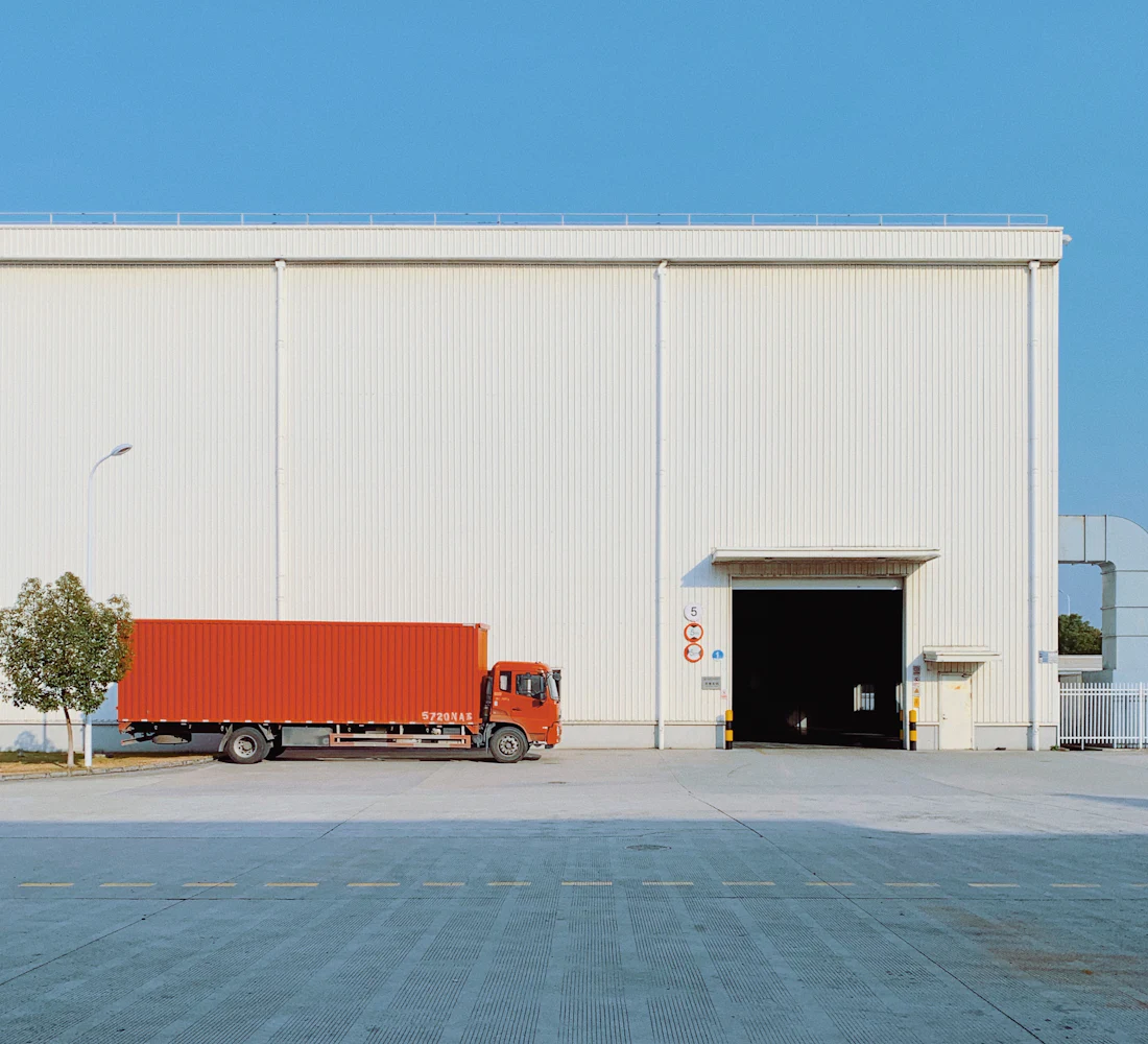 A red freight truck parked at a warehouse door